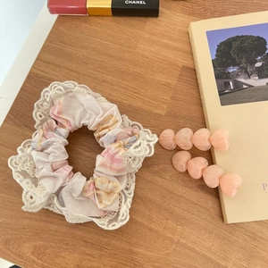 Détail d'un chouchou floral en dentelle et de deux barrettes à cheveux roses en cœur