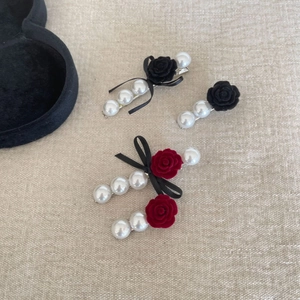 Close-up of vintage velvet rose and pearl hair clips set against a textured fabric