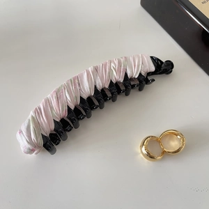 Close-up of a floral satin banana hair clip and gold hoop earrings on a white surface