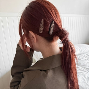 Detail of leopard print faux fur hair clips styled on long auburn hair side profile