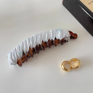 Detail of tortoise shell banana clip with white ribbon and gold hoop earrings