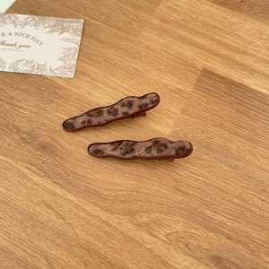 Pair of vintage leopard print hair clips with fuzzy texture on a wooden background