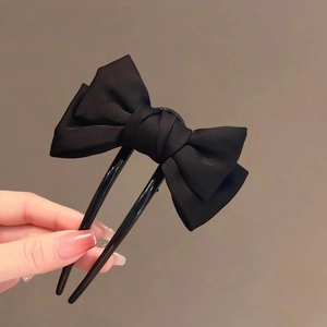 Detail view of a large black satin bow hair fork with double-tooth metal U-shape design