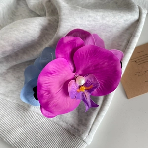 Dettaglio delle mollette per capelli a forma di orchidea con petali in tessuto e perle