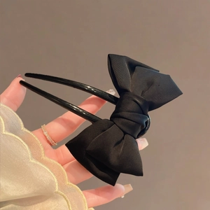Detail of a large black fabric bow hair clip with a sturdy U-shaped hairpin fork structure