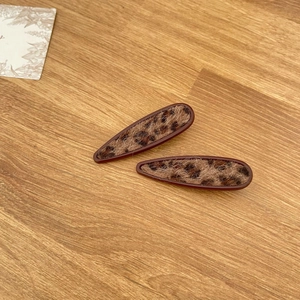 Detail shot of leopard print plush hair clips with dark brown frames on wood