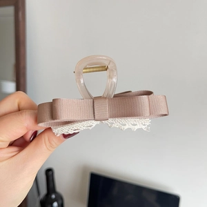 Pince à cheveux élégante avec double nœud et détails en dentelle rose clair
