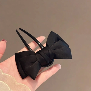 Close-up of elegant black fabric bow hair pin with matte satin finish for classic styling