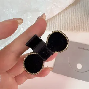 Close-up of a black velvet bow hair claw clip with sparkly rhinestone trim detail