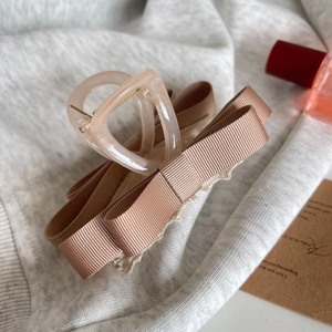 Détail d'une pince à cheveux avec nœud en ruban abricot sur un support texturé doux