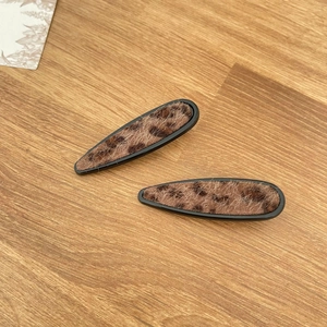 Macro shot of leopard print hair clips with fuzzy texture on a wooden background