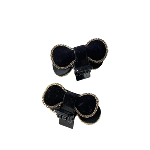Pair of black velvet bow hair claws with sparkling gold rhinestones on white background