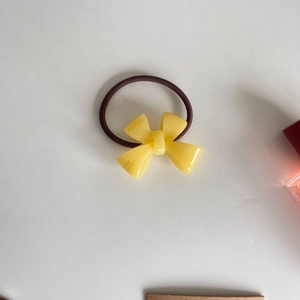 Close-up of yellow acrylic bow ornament on high-elasticity brown hair tie band