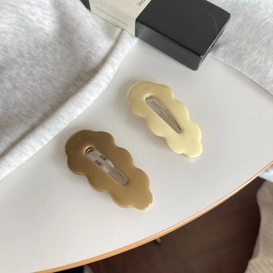 Detail von wellenförmigen Haarspangen in Creme und Olivbraun mit robustem Metallclip