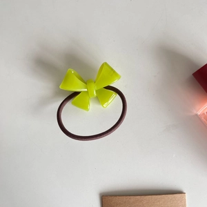 Close-up of translucent green acrylic bow hair tie with dark brown elastic band
