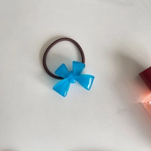 Detail of blue translucent resin bow hair tie with elastic dark brown woven strap