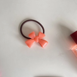 Detail of coral pink acrylic bow hair tie with SANS Hand engraving and elastic band