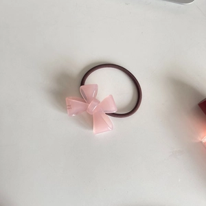 Detail view of pink acrylic bow hair tie with high-elasticity brown rubber band