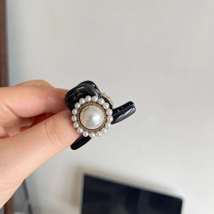Elegant black hair claw with a large baroque pearl surrounded by small pearls in gold metal