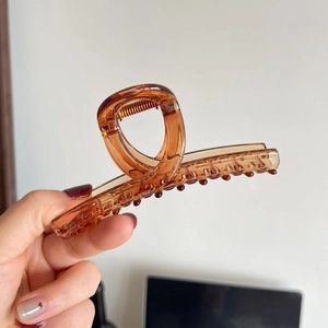 Detail showing high-quality transparent brown resin shark hair clip with gold metal spring