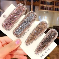 Detail of four colorful rhinestone hair clips in pink, blue, champagne and dark grey