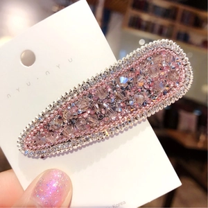 Macro di strass rosa e trasparenti su un fermaglio ovale con bordi di perline metalliche