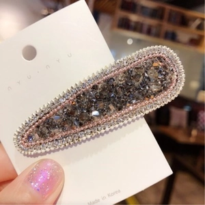 Dettaglio molletta coreana con strass marroni e bordi decorati con perline bianche