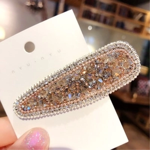 Dettaglio del fermaglio ovale con strass color champagne e bordo in cristalli argento