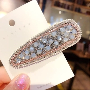 Dettaglio di fermaglio ovale vintage con perline azzurre e strass scintillanti