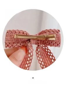 Close-up of pink lace bow hair clip showing detailed mesh texture and gold metal grip