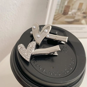 Elegante herzförmige Haarspangen mit Perlen und Strasssteinen auf Kaffeedeckel-Hintergrund