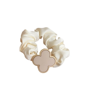 Elastic cream satin scrunchie with a gold-rimmed clover charm for hair styling