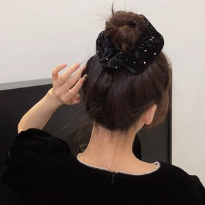 Chouchou élégant en velours noir avec clous dorés porté dans un style rétro Hepburn