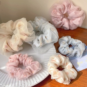 Detail view of floral organza scrunchies in pink, light blue and beige colors