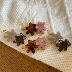 Close-up of acetate bear hair clips with gold metal base on white knit fabric