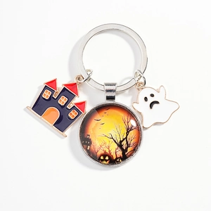 Halloween keychain featuring a glass pumpkin charm, enamel castle, and white ghost pendant