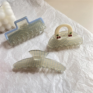 Detailed view of checkered hair claws in blue and cream with red cherry patterns