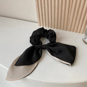 Close-up of elegant camellia hair scrunchie in black and beige satin fabric texture