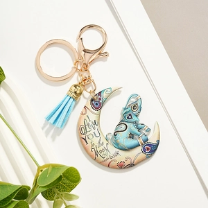 Detail of crescent moon elephant keychain with blue tassel and gold metal ring