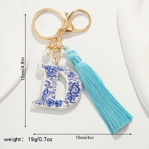 Detail view of blue porcelain style letter D keychain with tassel and pearl charm