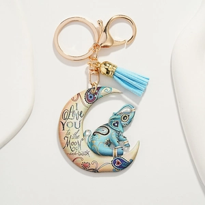 Detailed view of moon-shaped elephant keychain with light blue tassel and golden hardware