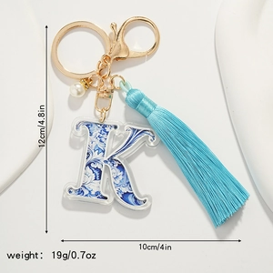 Detailed view of blue floral letter K keychain with light blue tassel and white pearl