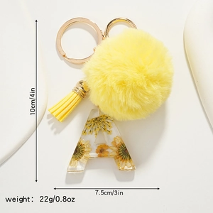 Letter A resin keychain with yellow dried flowers, faux fur pompom and tassel detail