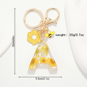 Détail du porte-clés lettre A en résine avec fleurs jaunes séchées et abeille