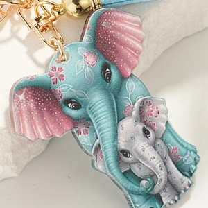 Detail of blue acrylic mother and child elephant keychain with golden metal clasp and tassel