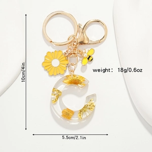 Détail du porte-clés lettre C en résine avec fleurs jaunes séchées, abeille et mesures