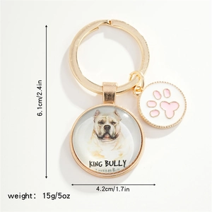 Close-up of golden dog keychain with American Bully image and pink paw charm detail