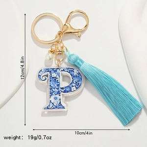 Detail of letter P keychain with blue floral pattern, silk tassel and pearl bead accessory