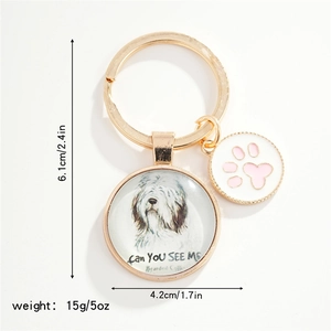 Detailed view of dog charm keychain with round glass pendant and pink paw accessory