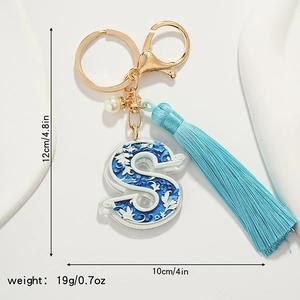 Detailed view of letter S porcelain pattern keychain with blue tassel and white pearl